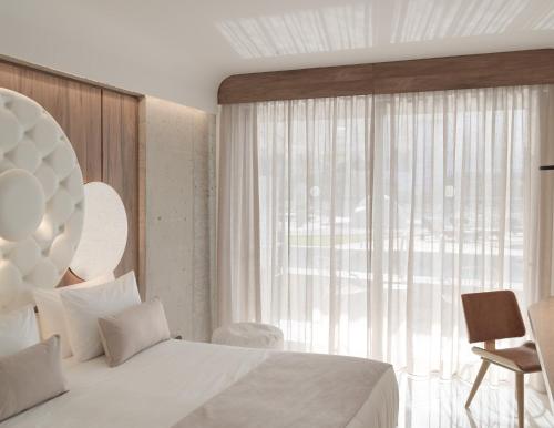 a bedroom with a white bed and a large window at Nautilux Rethymno by Mage Hotels in Rethymno Town