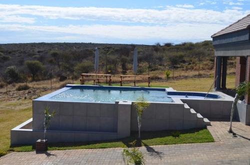 a swimming pool in a yard with two benches at Tuscany Hill Manor in Hartswater