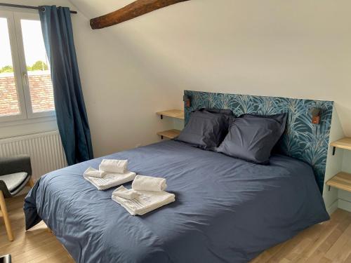 Un dormitorio con una cama azul con toallas. en Le QG 28 en Nonvilliers-Grandhoux