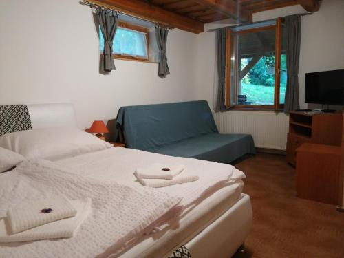 um quarto com 2 camas, um sofá e uma televisão em Flóra Apartmanok em Kehidakustány