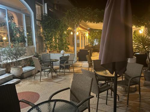 patio con sedie, tavoli e ombrellone di Hotel Pighi a Kriopigi