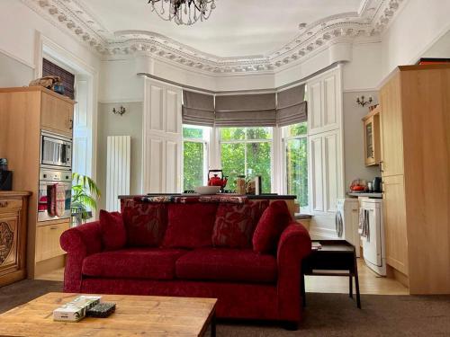 a living room with a red couch and a window at Beautiful Double Room in Idyllic West End Townhouse in Glasgow