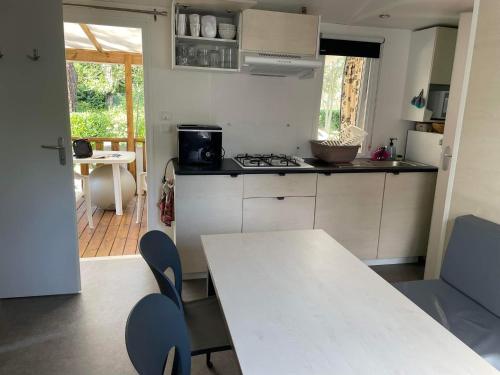 - une cuisine avec une table et des chaises blanches dans l'établissement Mobil home Argelès sur mer, à Plage dʼArgelès