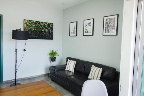 a living room with a black couch and some pictures at Nidah Condominios in Durango