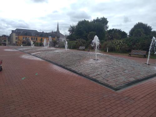 a brick walkway with water fountains in a park at Chambre agréable au calme in Saint-Hilaire-Petitville