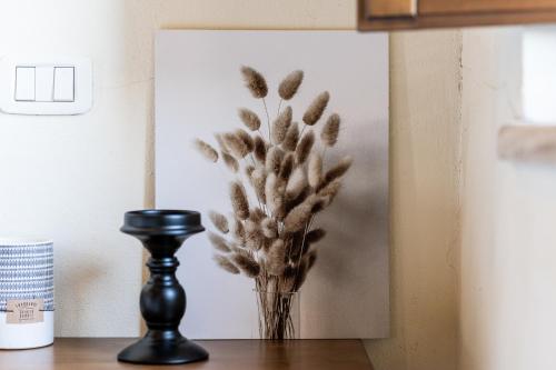 a vase of flowers on a table with a picture at Hotel More di Cuna in Monteroni dʼArbia