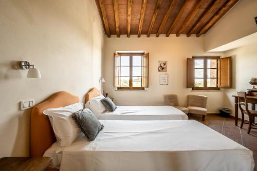 two beds in a room with a table and chairs at Hotel More di Cuna in Monteroni dʼArbia
