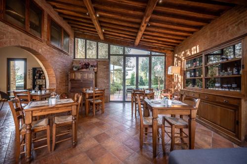 un ristorante con tavoli e sedie in legno e finestre di Hotel More di Cuna a Monteroni dʼArbia