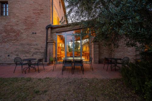 a patio with tables and chairs in front of a brick building at Hotel More di Cuna in Monteroni dʼArbia