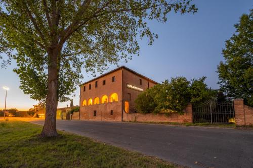 a brick building with a tree next to a street at Hotel More di Cuna in Monteroni dʼArbia