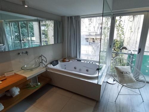 a bathroom with a tub and a chair and a window at CasaCalma Hotel in Buenos Aires