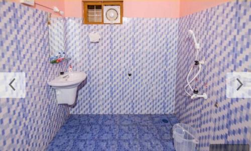 a blue tiled bathroom with a sink and a toilet at Nandanam Villa in Kaniyāmbetta