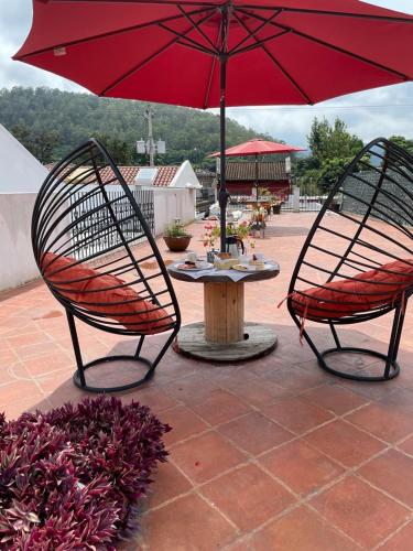 two chairs and a table with a red umbrella at Nico Hotel in Antigua Guatemala