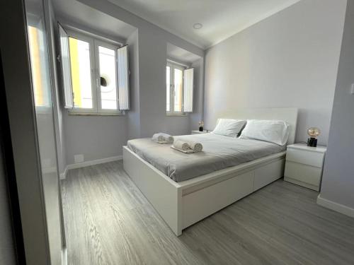 a white bedroom with a bed and two windows at CASA ALCOCHETANA in Alcochete