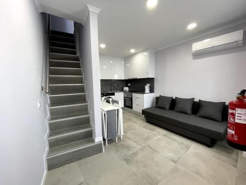 a living room with a black couch and a kitchen at CASA ALCOCHETANA in Alcochete