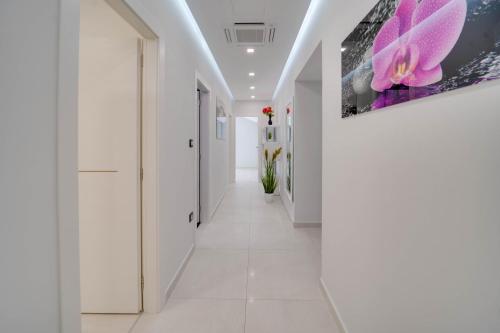un couloir avec des murs et des sols blancs ainsi qu'une peinture murale. dans l'établissement BLACK DIAMOND Apartment, à Vilanija