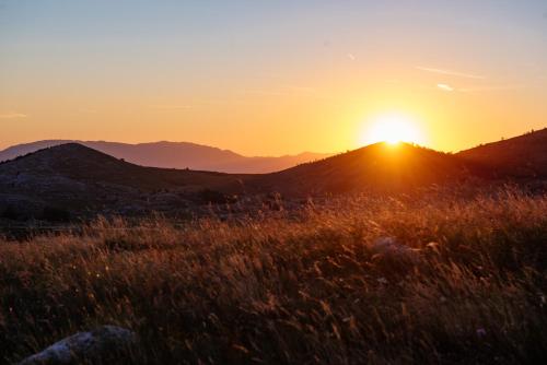 a field of grass with the sunset in the background at Stairway - Vučje in Nikšić