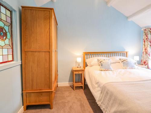 a bedroom with a bed and a wooden cabinet at Preswylfa in Blaenau-Ffestiniog