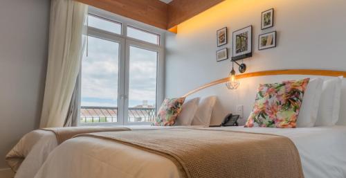 1 dormitorio con 1 cama grande y ventana en Hotel Monte Brasil, en Angra do Heroísmo