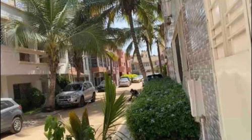 達喀爾的住宿－Appartement Luxe idéalement situé à Dakar，一条有汽车停放在棕榈树建筑旁边的街道