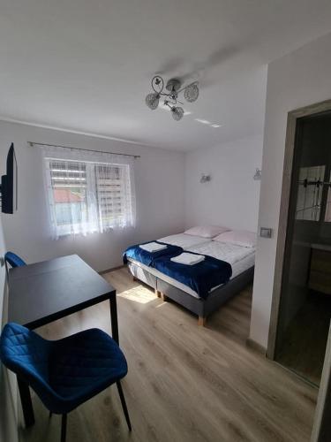 a bedroom with a bed and a table and a chair at Zacisze na Roztoczu in Horyniec