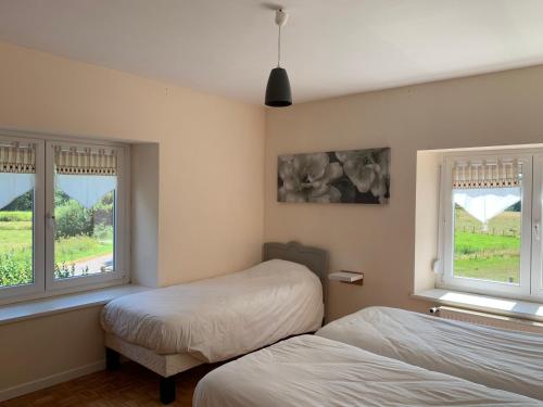1 dormitorio con 2 camas y 2 ventanas en L'oriere des Bois, en Ronchamp