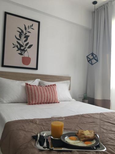 una bandeja de comida y zumo de naranja en una cama en Blue View Suites en Chorafakia