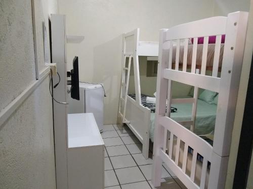 a room with two bunk beds and a television at Pousada Emilly in Joinville