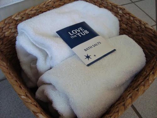 a basket filled with white towels with a book at AmericInn by Wyndham Sioux City in Sioux City