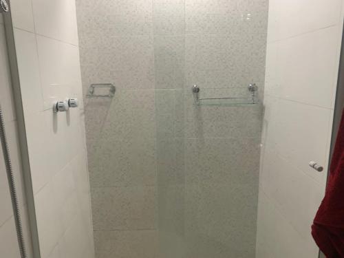 una ducha con puerta de cristal en un baño en Apartamento Veleiros da Ilha - Praia do Tombo, en Guarujá