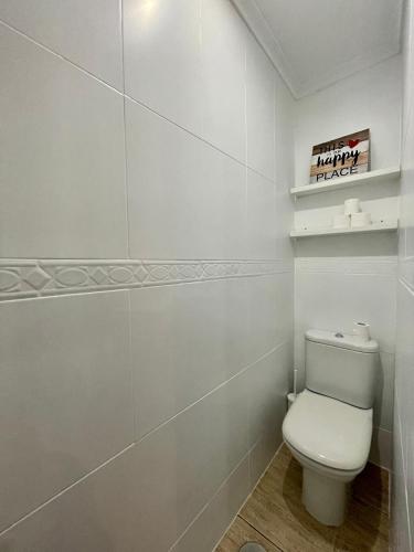 a bathroom with a toilet and a happyart sign on the wall at A Das Marias GALLERY in Ourense