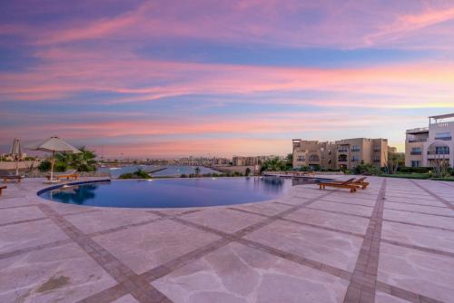 a swimming pool with a sunset in the background at Golden Apartments El Gouna in Hurghada