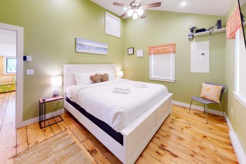 a bedroom with a large white bed and a fan at Rising Tide Cottage in Cushing