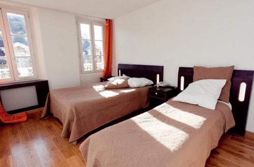 a hotel room with two beds and two windows at Hôtel Belle Fontainebleau in Fontainebleau