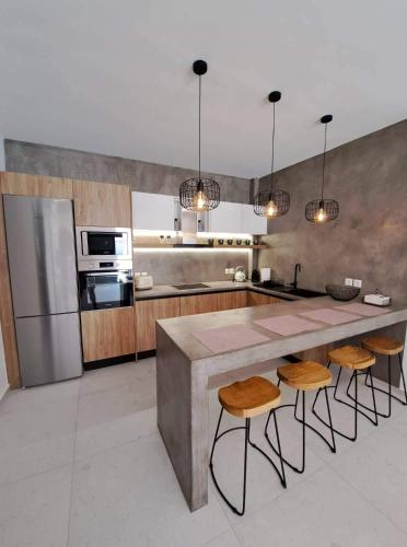 una cucina con un grande bancone e alcuni sgabelli di Courtyard Luxury Suites “MARIANTHI” a Pefki Rhodes