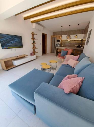 a living room with a blue couch and a kitchen at Courtyard Luxury Suites “MARIANTHI” in Pefki Rhodes
