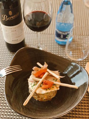 a plate with a sandwich with chopsticks and a bottle of wine at Don Paco in Llanes
