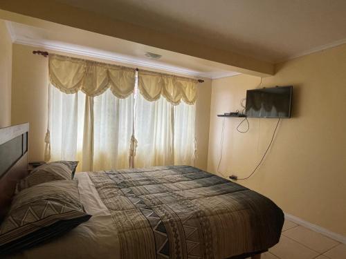a bedroom with a bed and a television on the wall at La casa de Ely in Iquique