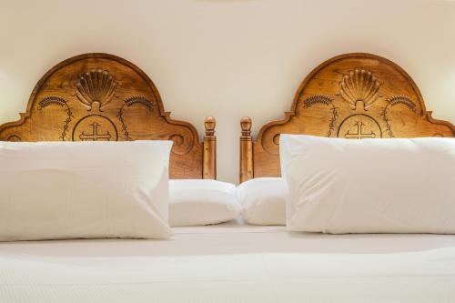 1 cama con 2 cabeceros de madera y almohadas blancas en Don Paco en Llanes