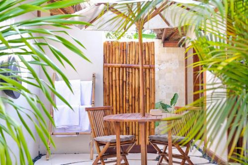 a table and chairs in a room with palm trees at Villa Marina in Gili Air