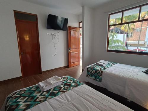 a room with two beds and a tv on the wall at Hotel El Bosque in Jaén