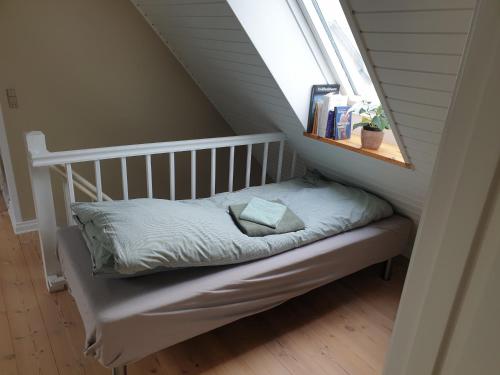 a small bed in a room with a window at Lejlighed vest for Christiansfeld in Christiansfeld