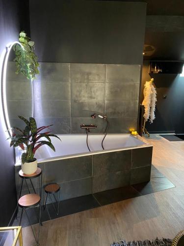 La salle de bains est pourvue d'une baignoire avec une plante et deux tabourets. dans l'établissement Suite Gatsby - balançoire et baignoire duo - Luxe et charme - climatisation, à Eyrans-de Soudiac