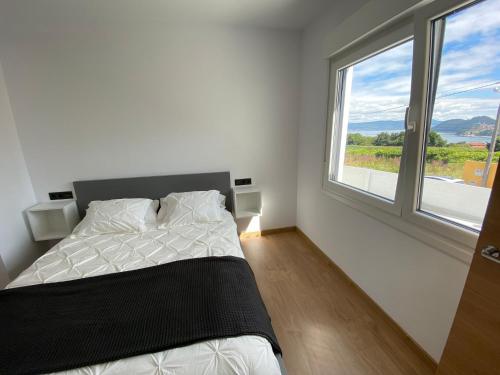 sypialnia z łóżkiem i dużym oknem w obiekcie Apartamentos Turisticos Costa Celeiro: Portomaior, Agrelo, Covelo Lapamán w mieście Bueu