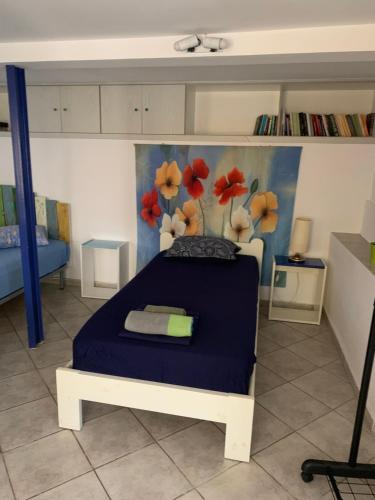 a bedroom with a blue bed and a painting of flowers at studio in old town of Mytilene in Mytilini