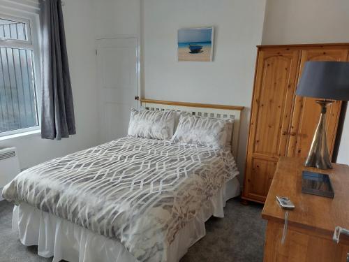 ein Schlafzimmer mit einem Bett und einem Schreibtisch mit einer Lampe in der Unterkunft Cuddys Corner in Beadnell