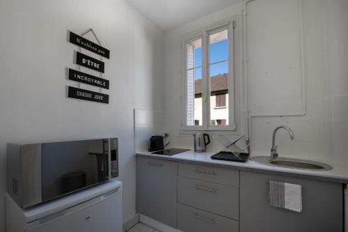 een keuken met witte kasten, een wastafel en een raam bij Studio cosy en centre-ville Proche de Paris in Pierrefitte-sur-Seine