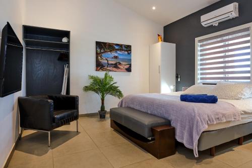 a bedroom with a bed and a chair at Bubali Luxury Apartments - Adults Only - Wheelchair Friendly in Palm-Eagle Beach