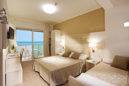 ビビオーネにあるHotel Mayerのベッドルーム1室(ベッド2台付)、海を望むバルコニーが備わります。