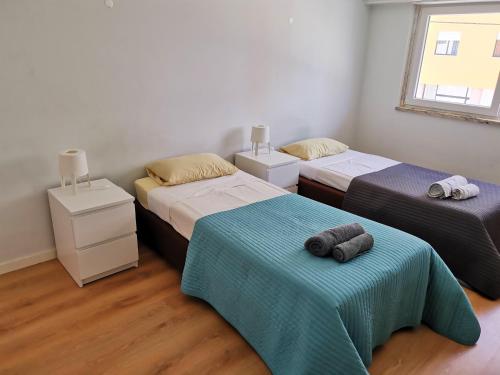 een slaapkamer met 2 bedden en handdoeken bij Sal Guest House in Costa da Caparica